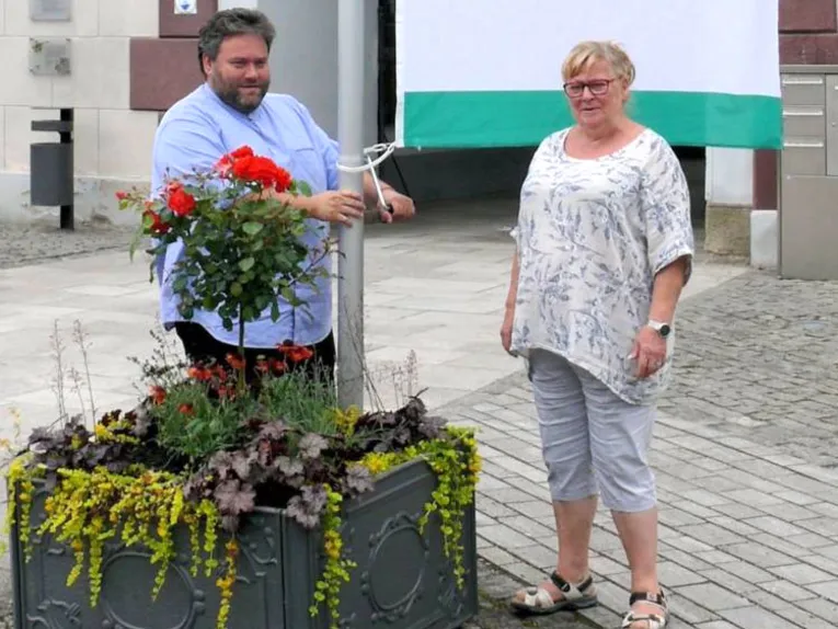 Zwei Personen h&auml;ngen die Friedensfahne am Rathaus Meiningen auf