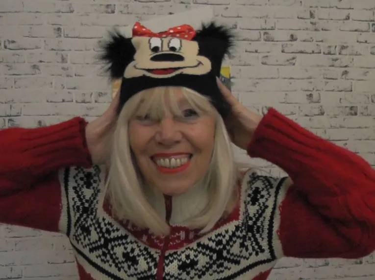 Eine Frau mit Norwegerpulli und Micky Maus-Strickmütze.