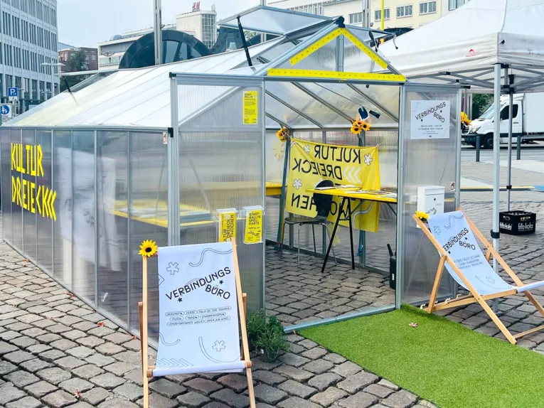 Das Verbindungsb&uuml;ro wurde von der B&uuml;rogemeinschaft Sebastian Moock w&auml;hrend der Kulturdreieck Festwochen auf dem Opernplatz installiert als ein kulturelles Gew&auml;chshaus, das die Menschen, Institutionen und Gesch&auml;fte im Kulturdreieck verbindet.