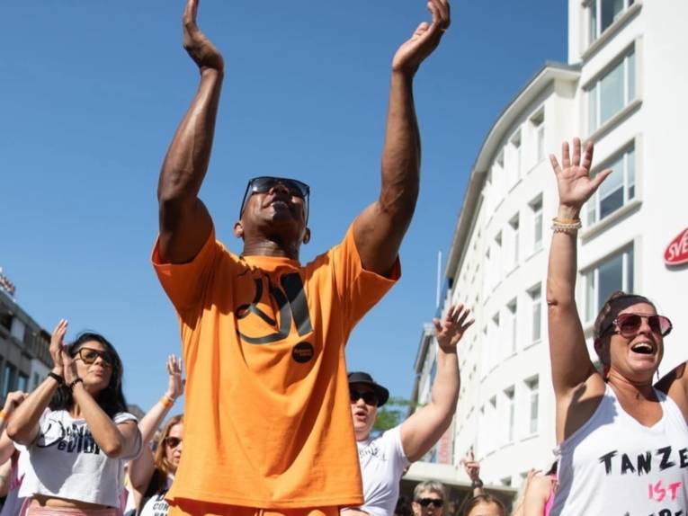 Mehrere Menschen, die draußen vor Gebäuden tanzen