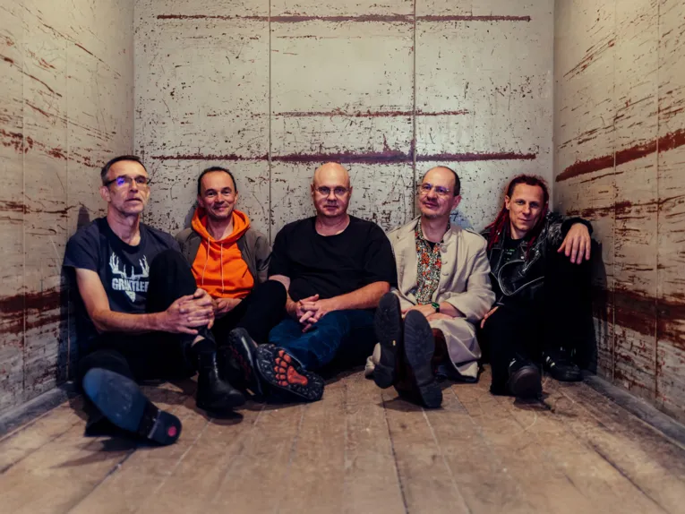 Zu sehen ist die Band „Brutal verschimmelt“. Die Bandmitglieder sitzen auf dem Boden.