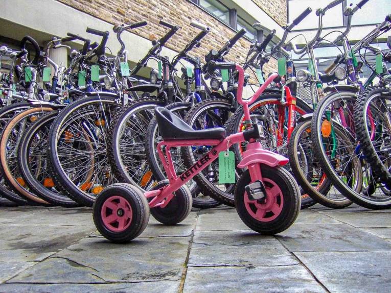 pinkfarbenes Dreirad vor Fahrrädern für eine Versteigerung