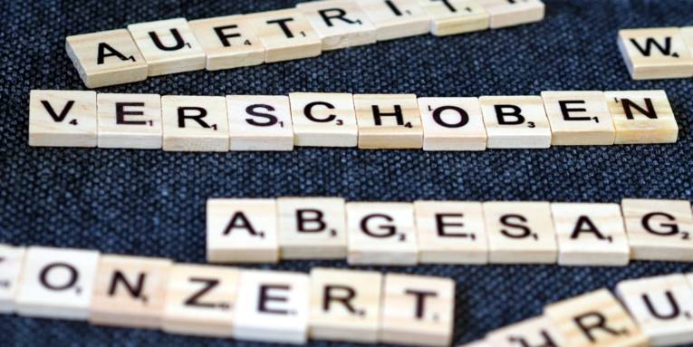 Holzplättchen mit Buchstaben bilden verschiedene Worte. Das Wort "Verschoben" ist scharf lesbar, während andere Worte unscharf sind.
