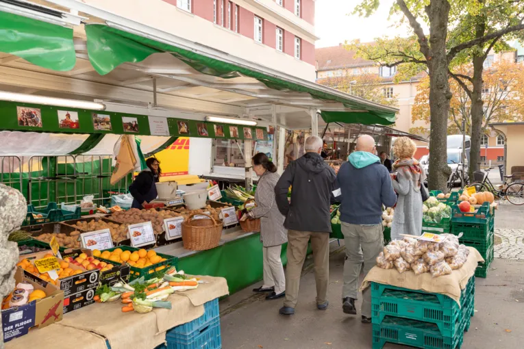 Menschen kaufen Obst und Gem&uuml;se an einem Marktwagen.