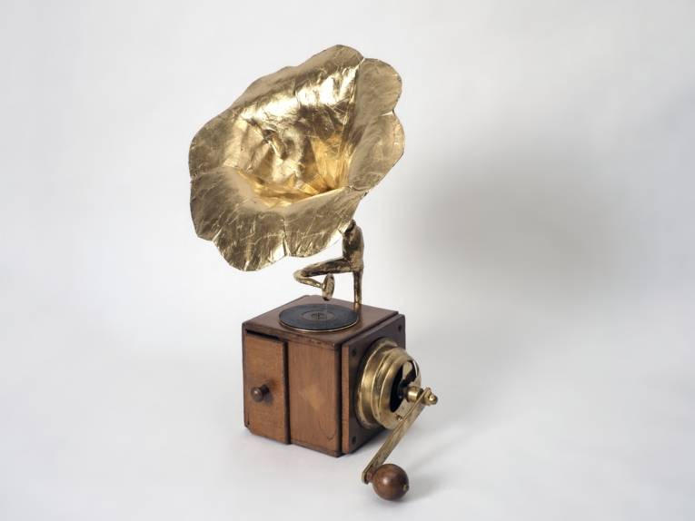 Das Bild zeigt ein Grammophon, das aus einer Kaffeemühle und einem Trichter aus Goldfolie zusammengesetzt ist