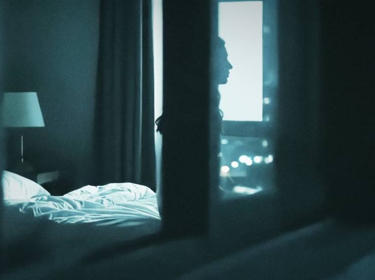 Zu sehen ist eine Fotografie eines Schlafzimmers, das in Blautönen gehalten ist. Das Bild dient als Promobild für das Theaterstück „In Schwebe/In Limbo“ im Theater an der Glocksee.