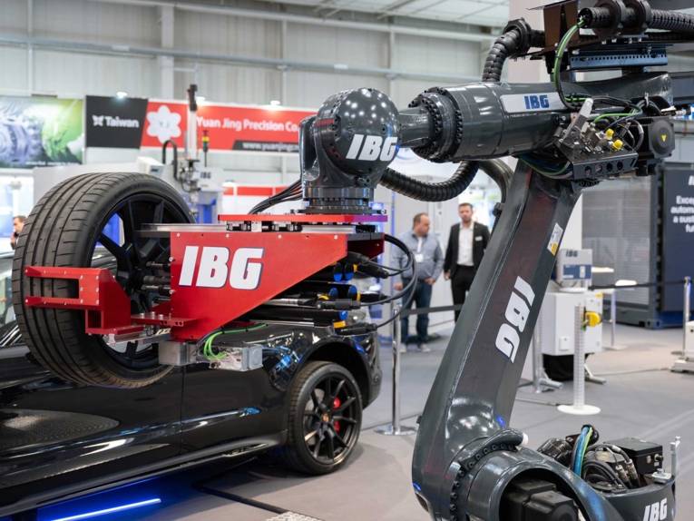 Industrieroboter hält einen Reifen in einer Messehalle