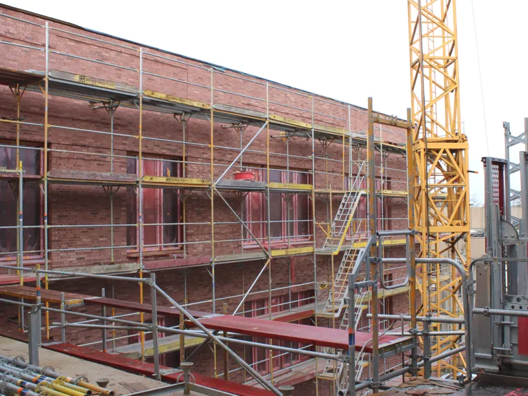 Au&szlig;enansicht von einem Neubau aus zwei Geschossen aus Ziegelwand, davor ein Bauger&uuml;st