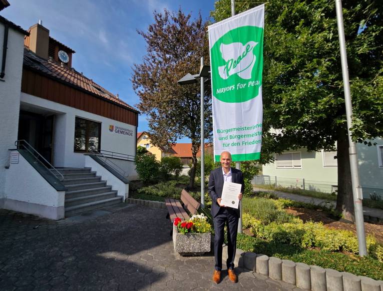 Großenseebach - Bürgermeister Jürgen Jäkel präsentiert stolz die Mitgliedsurkunde und Flagge von Mayors for Peace.