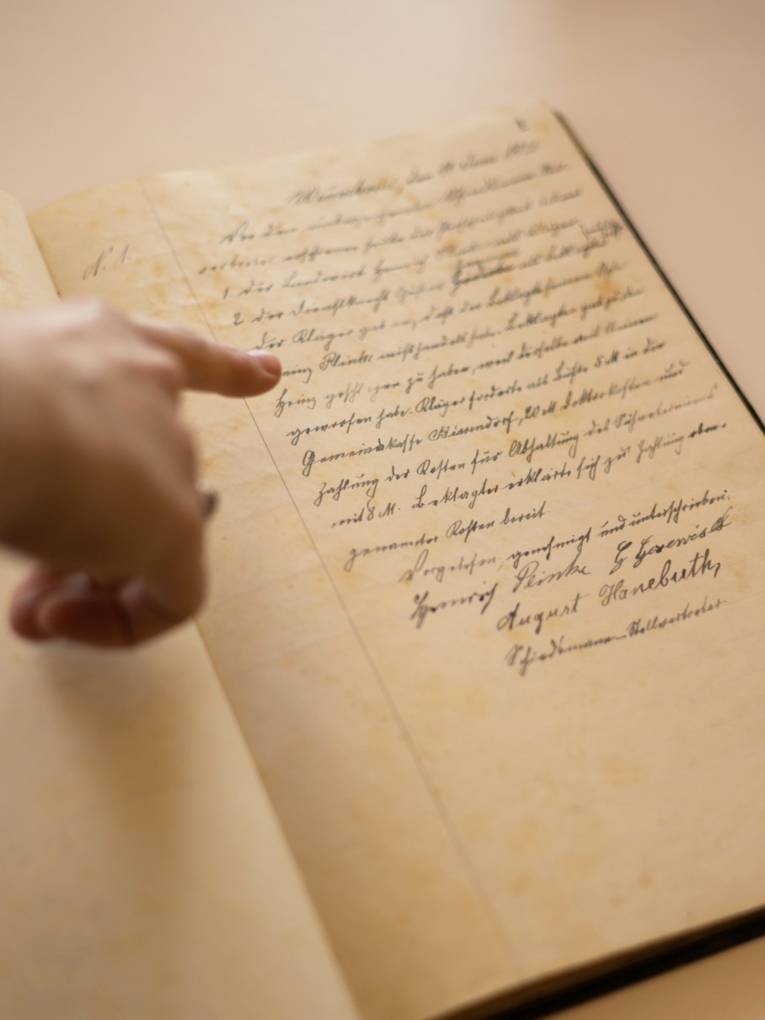 Eine Hand zeigt auf ein altes Dokument mit Handschrift.