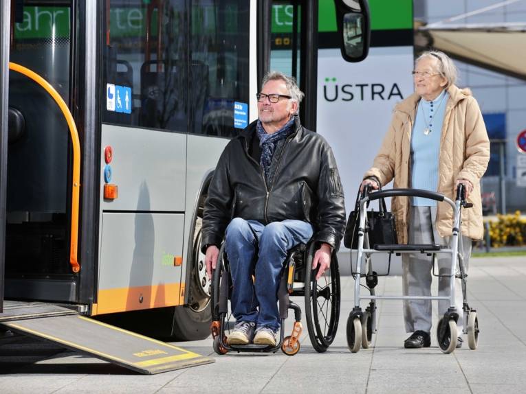 Ein Mann und eine Frau beim Mobilitätstraing am Bus mit ausgefahrener Rampe.