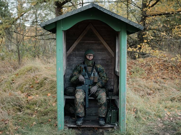 Ein bewaffneter Soldat sitzt in einem Pförtnerhäuschen