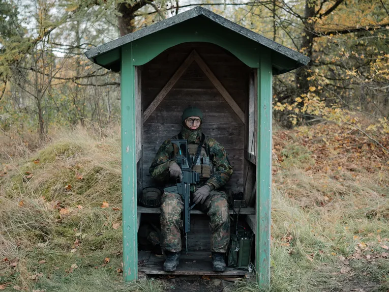 Ein bewaffneter Soldat sitzt in einem Pförtnerhäuschen