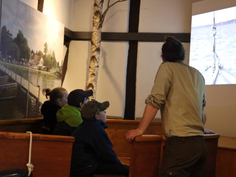 Drei Kinder und ein Naturparkranger schauen einen Film.