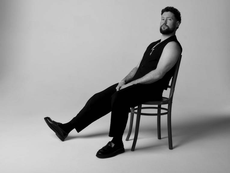 Der Sänger Calum Scott sitzt auf einem Stuhl