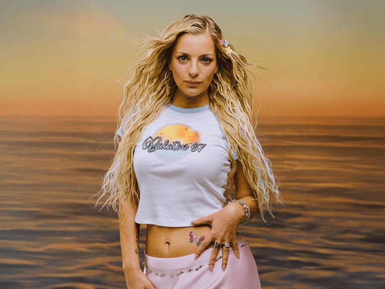 Zu sehen ist Laura Larsson vor einer Tapete mit Meeresmotiv bei Sonnenuntergang.
