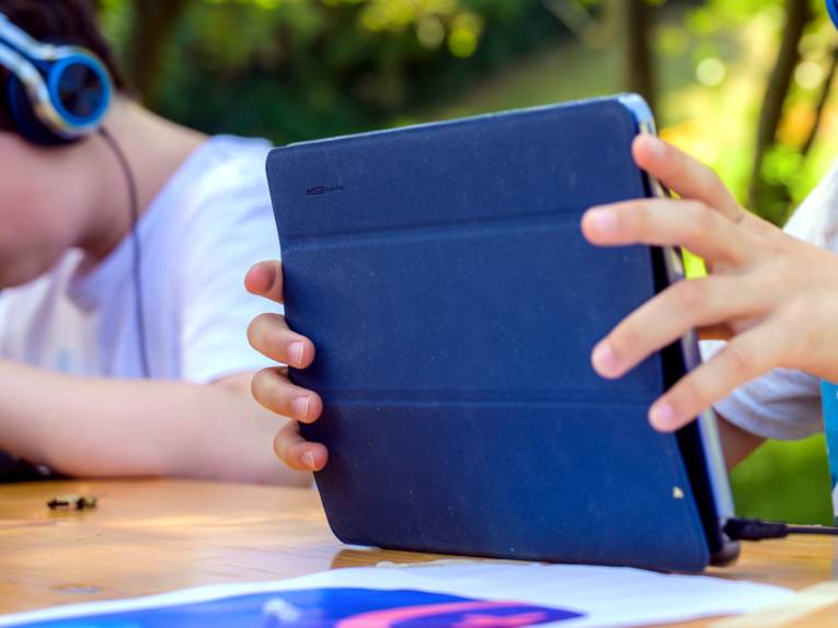 Kinderhände halten einen Tablet-Computer.