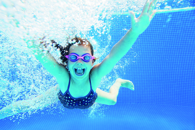 Kind mit Schwimmbrille unter Wasser, viele Luftblasen