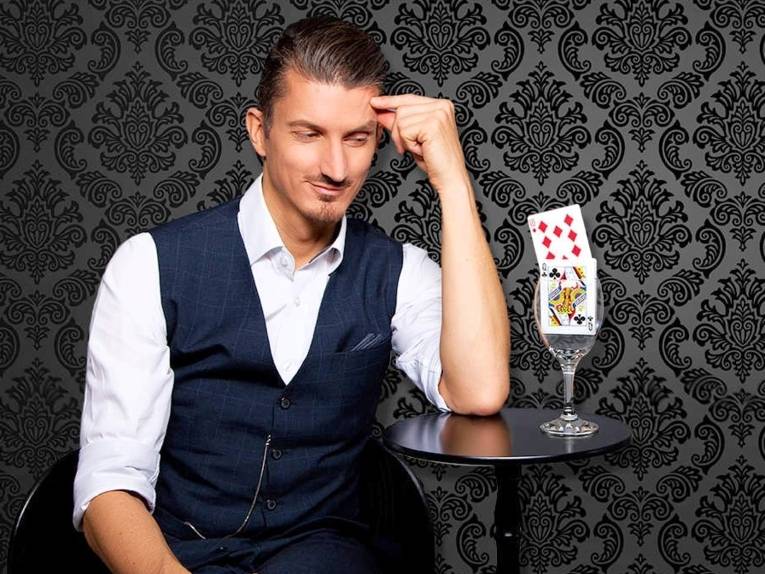 Mann mit einem Weinglas, in dem Spielkarten stecken