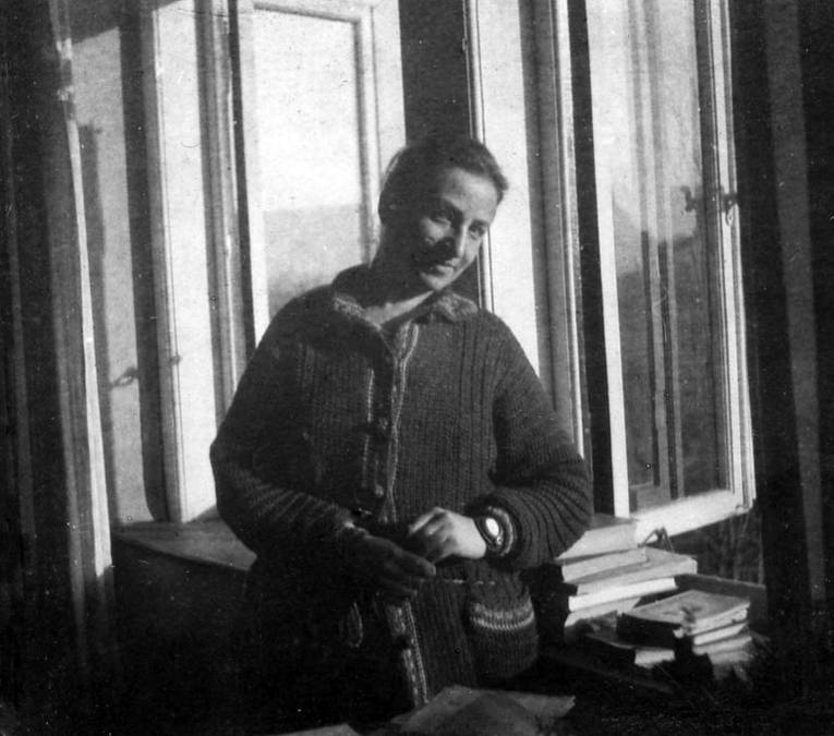 Ein schwarz-weiß Bild einer Frau an einem Fenster.