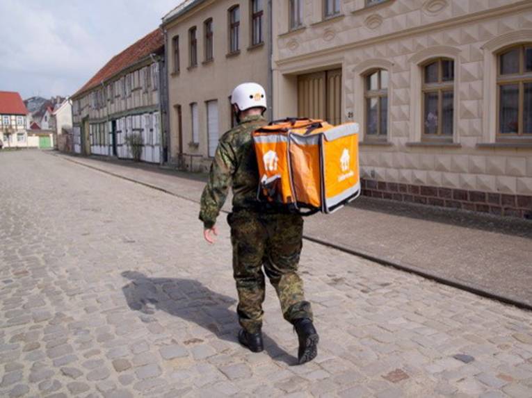 Ein Mann in Bundeswehr-Uniform und einem Auslieferungs-Rucksack auf den Schultern