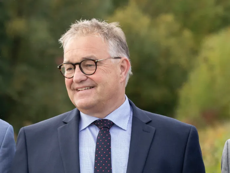 Hauke Jagau vor einem grünen Hintergrund im Freien.
