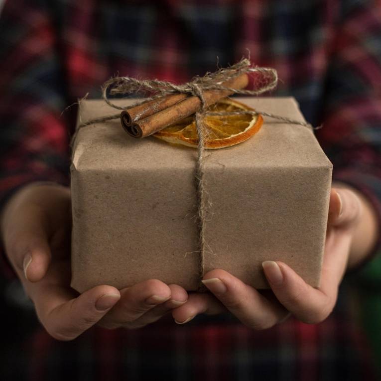 Ein nachhaltig eingepacktes Geschenk in den Händen einer Person
