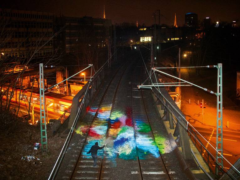 Ein buntes Bodengraffiti auf zwei Gleisen auf einer Brücke