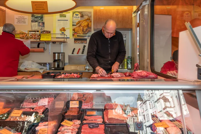 Ein Verk&auml;ufer schneidet Wurstwaren.
