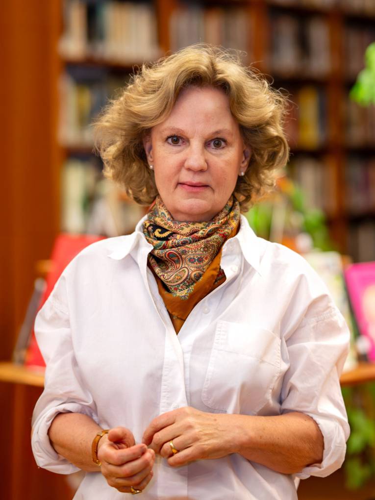 Portraitfotografie einer Frau mit einem verschwommenen B&uuml;cherregal im Hintergrund.