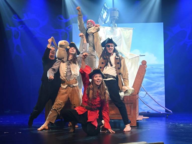 Zu sehen sind die Darstellenden als Piratinnen und Piraten verkleidet im Kindermusical „Anouk“ auf einer Bühne.