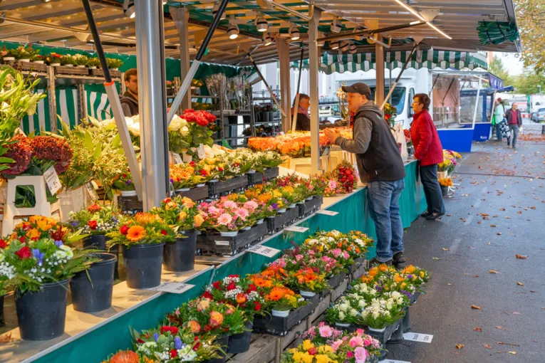 Menschen an einem Blumenwagen auf dem Wochenmarkt.