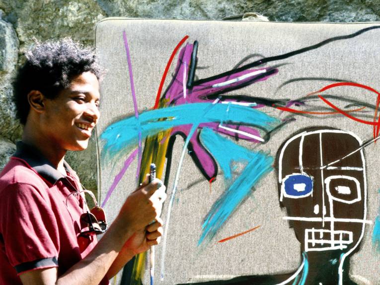 Ein junger Mann steht vor einer besprühten Wand