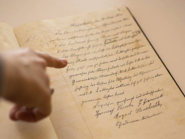 Eine Hand zeigt auf ein altes Dokument mit Handschrift.