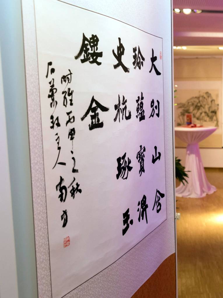 An einer Ausstellungswand hängt ein Papier mit chinesischen Schriftzeichen.