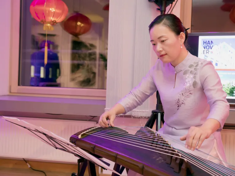 Eine Frau spielt auf einer chinesischen Wölbbrett-Zither.