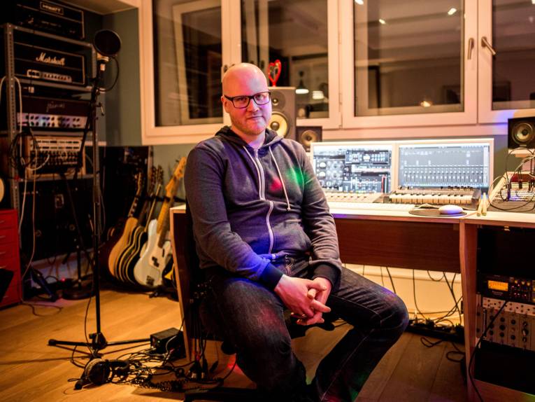 Ein Mann sitzt auf einem Stuhl in einem Tonstudio.