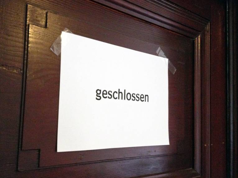Eine dunkle Holztür, an der ein weißes Blatt Papier mit der Aufschrift "geschlossen" hängt
