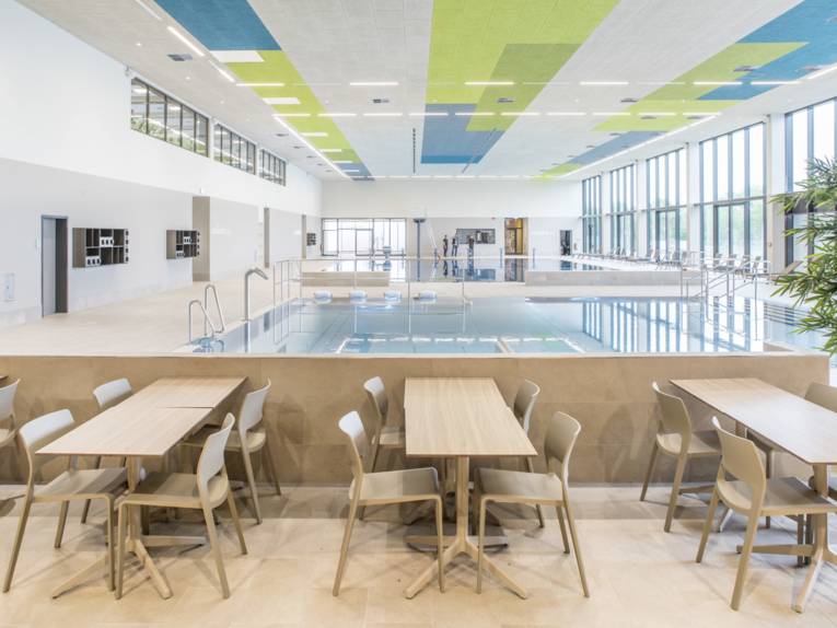 Tische und Stühle, im Hintergrund ein Schwimmbecken