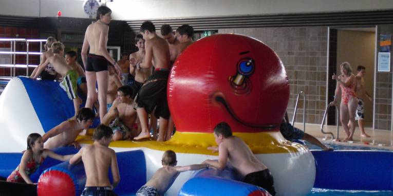 Kinder in einem Hallenbad, die auf einem aufgeblasenen Kraken toben