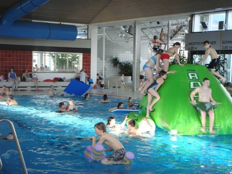 Kinder in einer Schwimmhalle mit einem grünen "Eisberg"