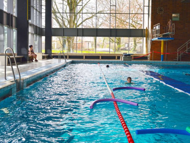 Schwimmbecken mit Schwimmern, Poolnudeln und Bahnbegrenzungen