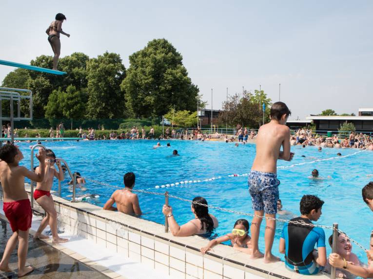 Jugendliche am Beckenrand im Freibad, ein Sprungturm
