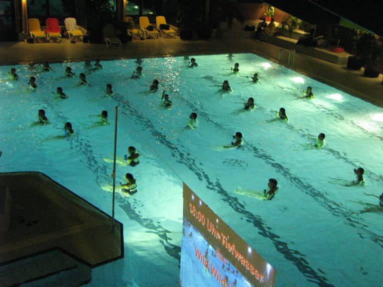 Menschen mit Auftriebshilfen in einem großen Hallenschwimmbecker