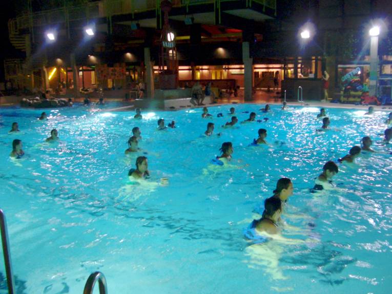 Badegäste haben sich im Schwimmbecken verteilt und folgen den Anweisungen des Trainers, der hier aber nicht im Bild zu sehen ist.