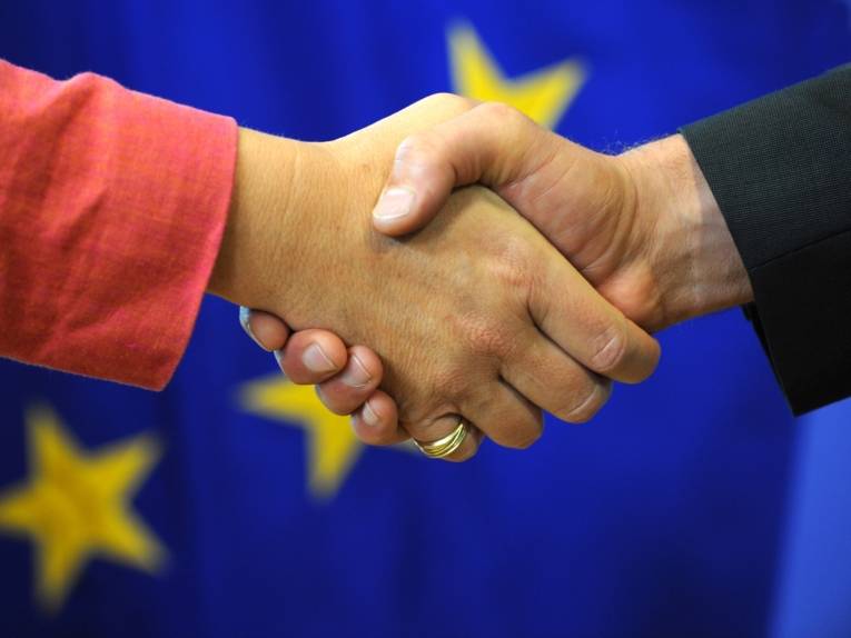 Handschlag vor der Europaflagge