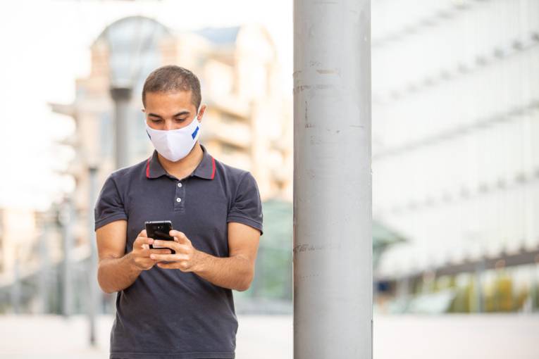 A man with a face mask looking at his smartphone