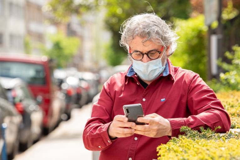 A man with a face mask using an application on his smartphone
