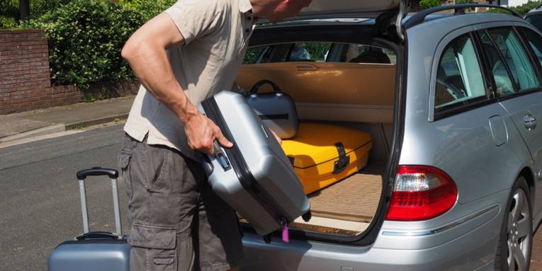 Ein Mann belädt seinen Kofferraum mit Reisegepäck.