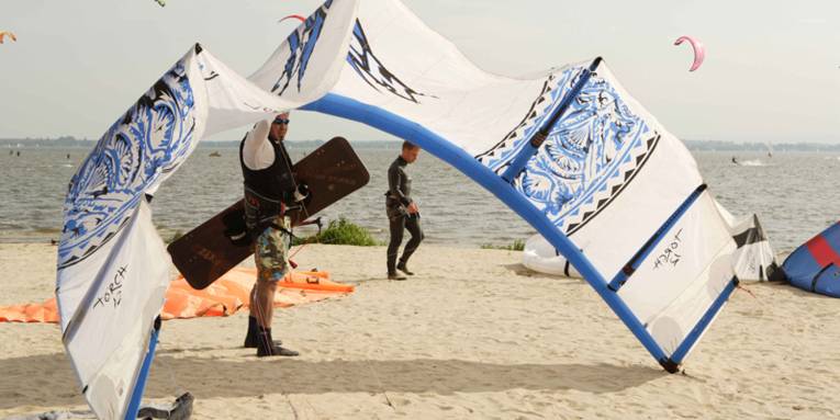 Ein Kitesurfer am Strand, der sein Segel in den Wind hält